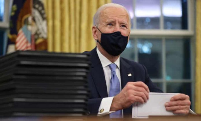 Joe Biden prepares to sign executive orders in the Oval Office on 20 January.