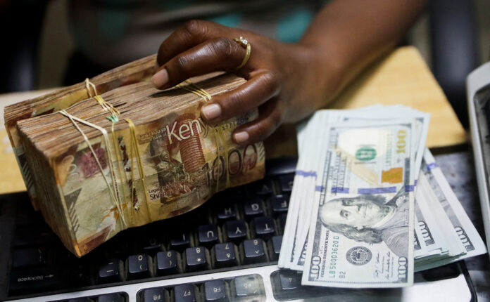 Teller handles Kenya shilling banknotes and U.S. dollar banknotes inside the cashier's booth at a forex exchange bureau in downtown Nairobi